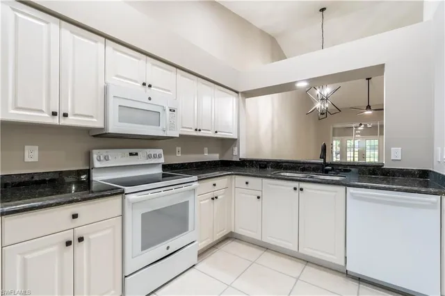 a kitchen with granite countertop white cabinets and white appliances