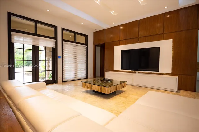 a living room with furniture a flat screen tv and a floor to ceiling window