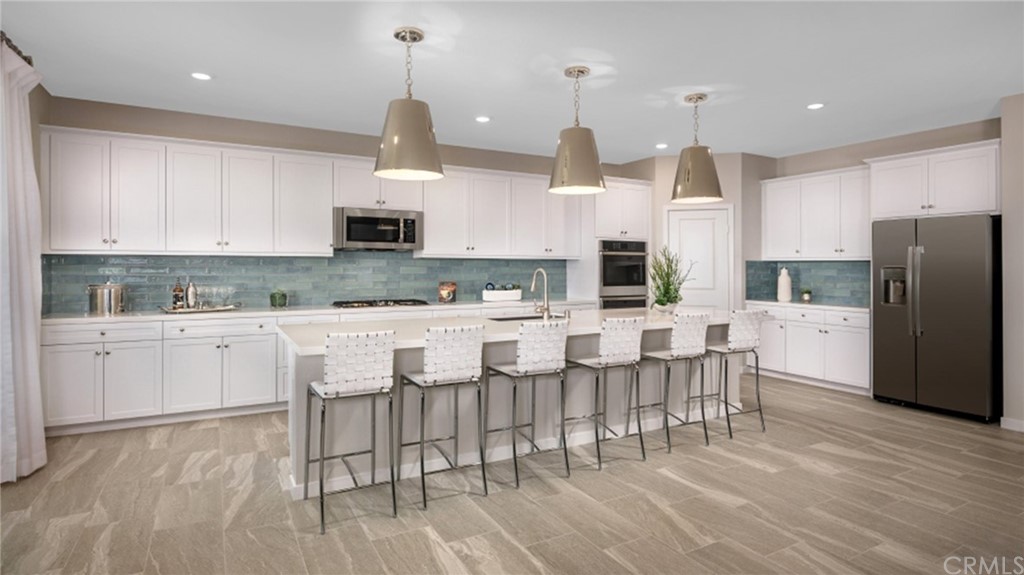 39614 Taffala Drive Indio, CA 92203 - Photo 4 of 14 a kitchen with stainless steel appliances kitchen island granite countertop a dining table chairs refrigerator and sink