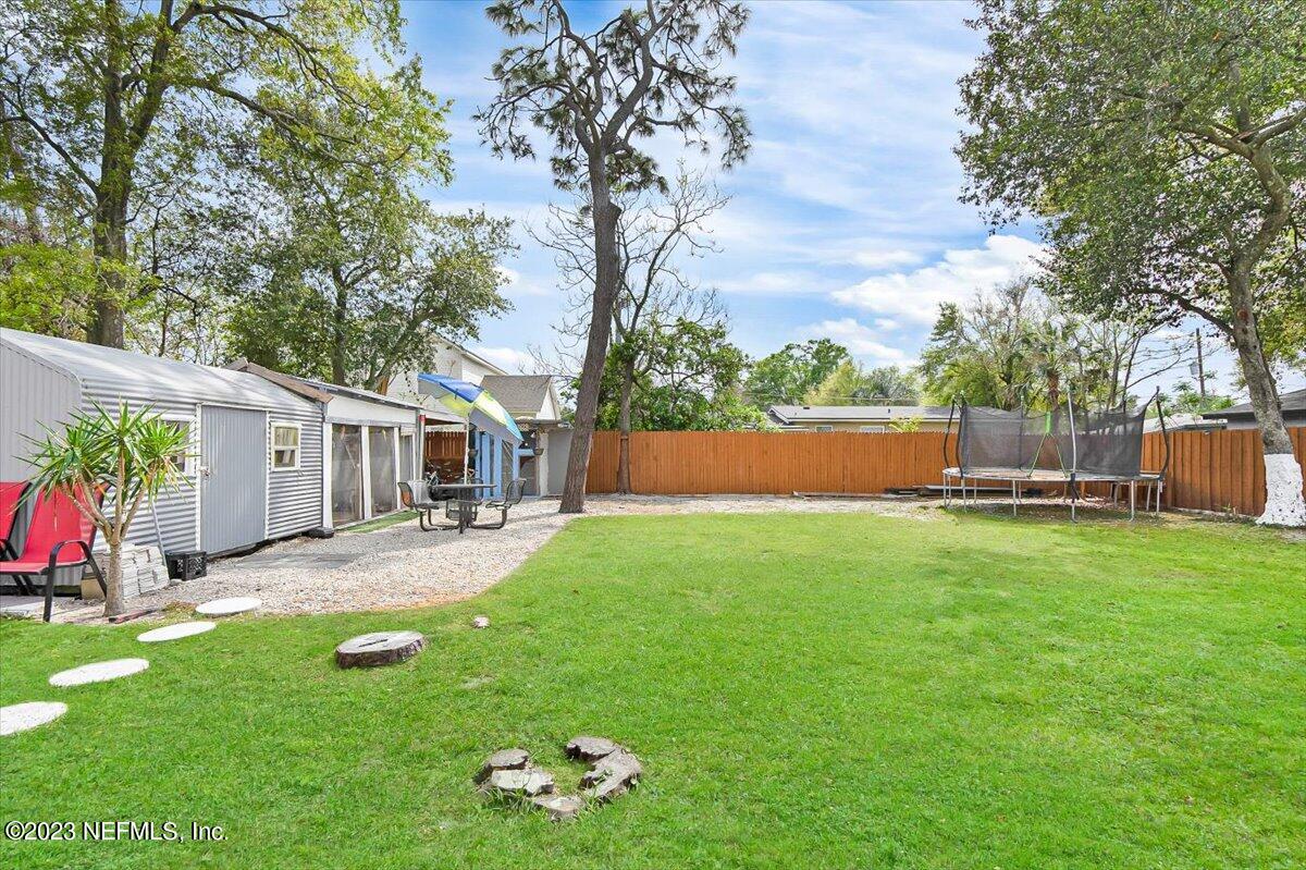 7240 Adele Court Jacksonville, FL 32277 - Photo 22 of 27 a view of backyard with table and chairs and potted plants and large trees