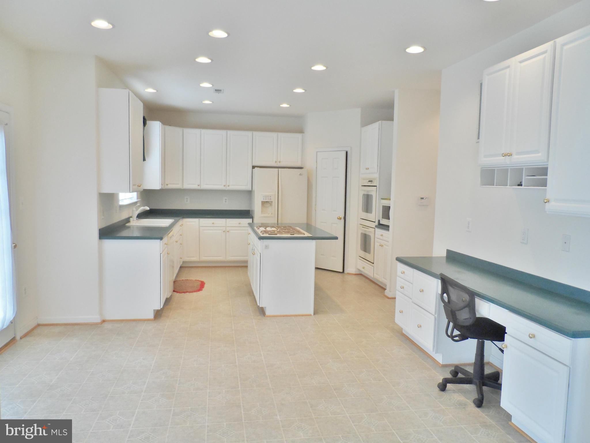 6281 Willowfield Way Springfield, VA 22150 - Photo 7 of 28 a kitchen with kitchen island white cabinets and stainless steel appliances