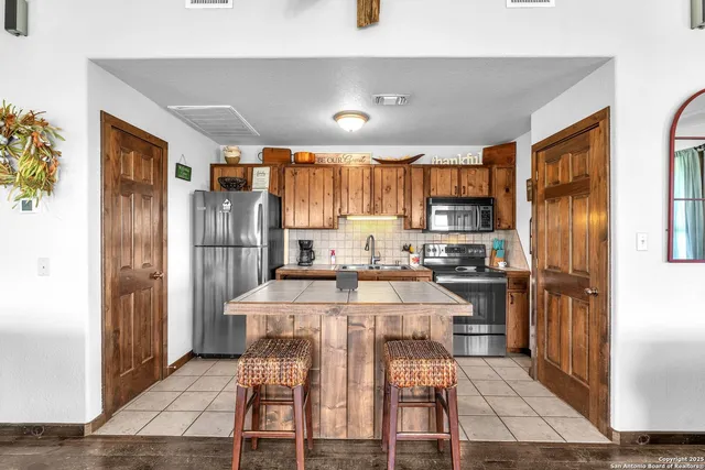 a kitchen with stainless steel appliances kitchen island granite countertop a refrigerator and a stove top oven