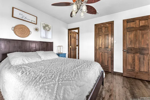 a bedroom with a bed and dresser with wooden floor