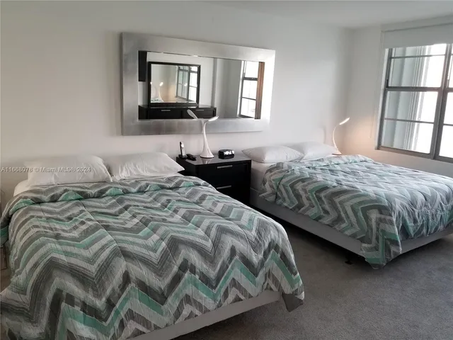 a bedroom with a bed and a flat tv screen on a dresser