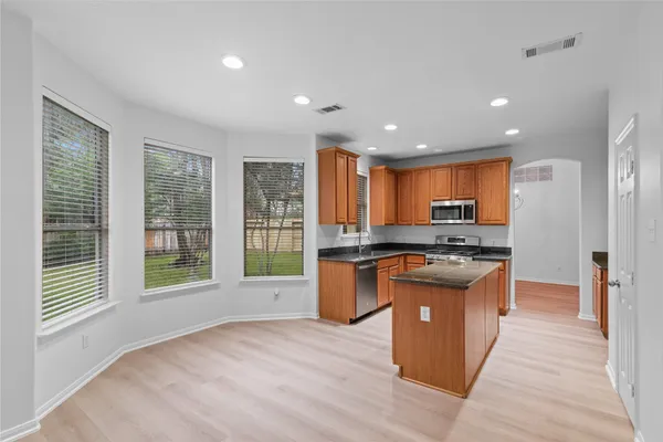 a kitchen with stainless steel appliances granite countertop a stove a sink and a microwave