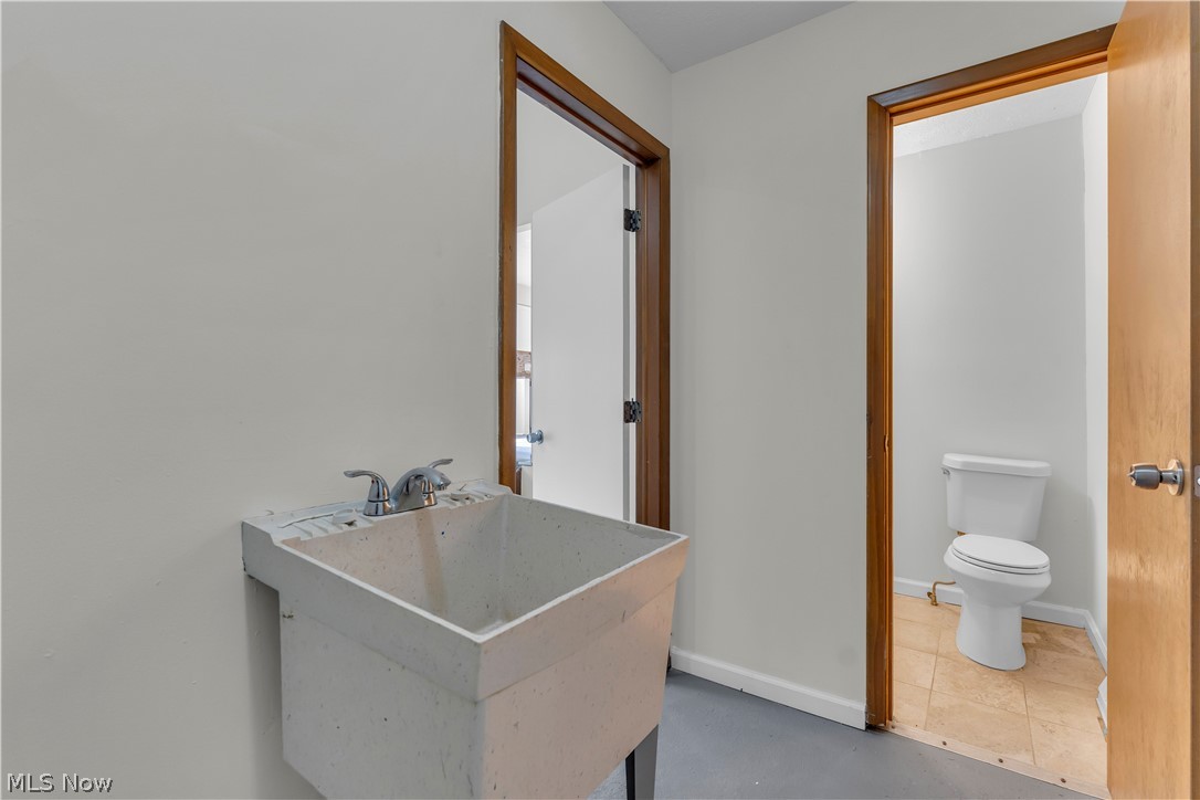 2540 Charney Road University Heights, OH 44118 - Photo 32 of 44 Utility room featuring a laundry tub with a dual-handle faucet, a white toilet, and tile flooring in the powder room