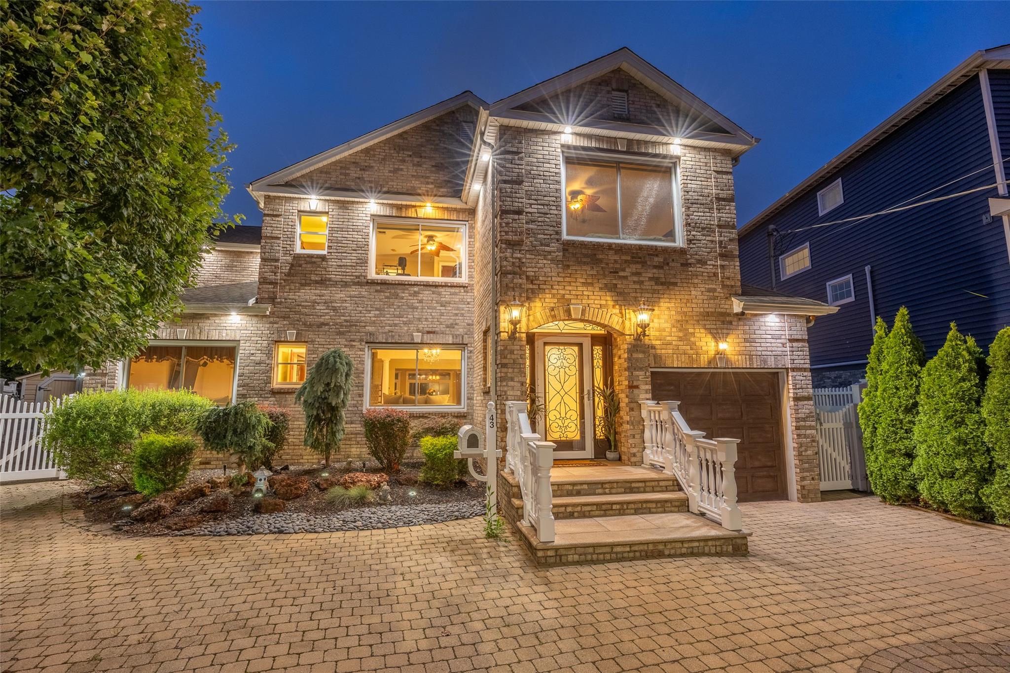 View of front of property featuring brick siding, decorative driveway, a gate, and a garage