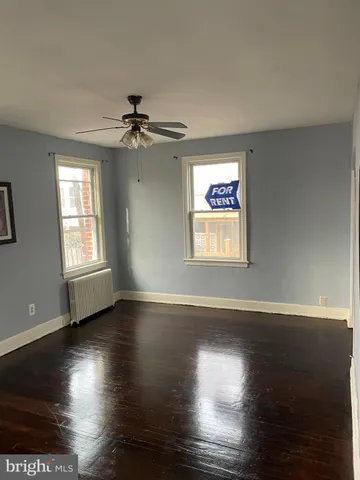 an empty room with wooden floor chandelier fan and windows