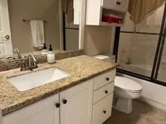 a bathroom with a granite countertop sink toilet and shower