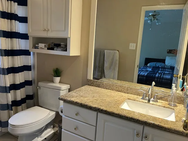 a bathroom with a granite countertop toilet a sink and a mirror