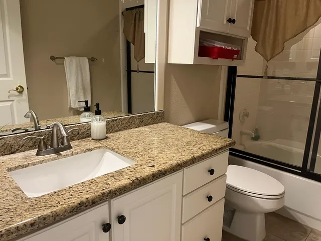 a bathroom with a granite countertop sink a toilet and a shower