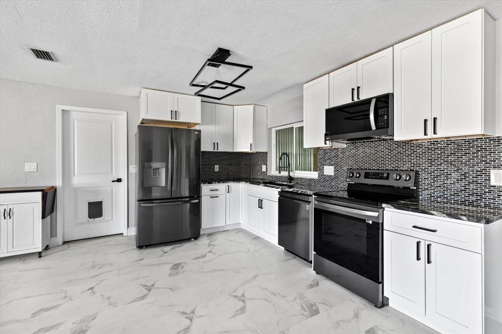 1436 Mardrake Road Daytona Beach, FL 32114 - Photo 5 of 37 a kitchen with stainless steel appliances granite countertop a refrigerator stove microwave and sink
