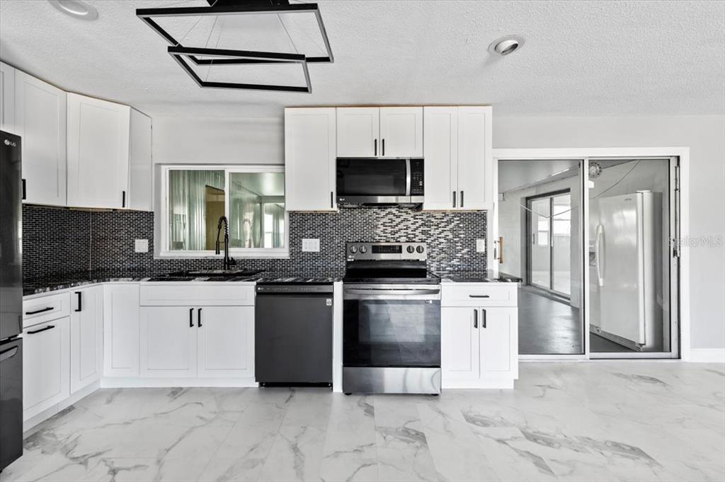 1436 Mardrake Road Daytona Beach, FL 32114 - Photo 6 of 37 a kitchen with stainless steel appliances granite countertop a stove top oven a sink dishwasher a refrigerator and a microwave