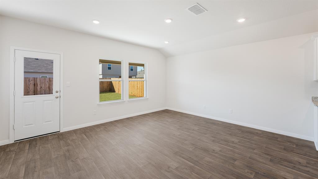 14021 Feinstein Street Manor, TX 78653 - Photo 9 of 25 Natural light floods this inviting living area, showcasing rich hardwood-style flooring and direct outdoor access.