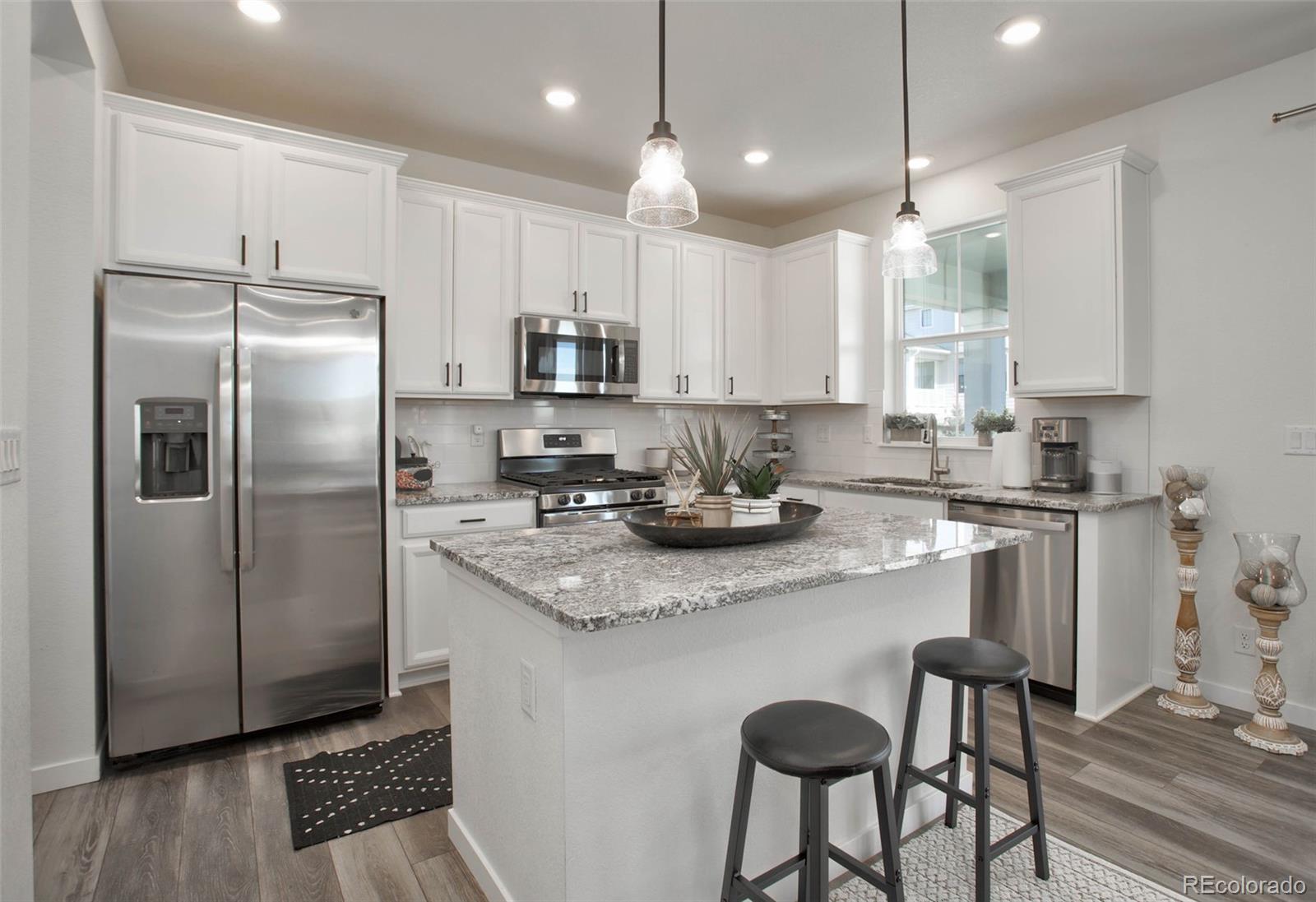1131 Williams Loop Elizabeth, CO 80107 - Photo 17 of 40 a kitchen with stainless steel appliances granite countertop a refrigerator a sink a stove a dining table and chairs