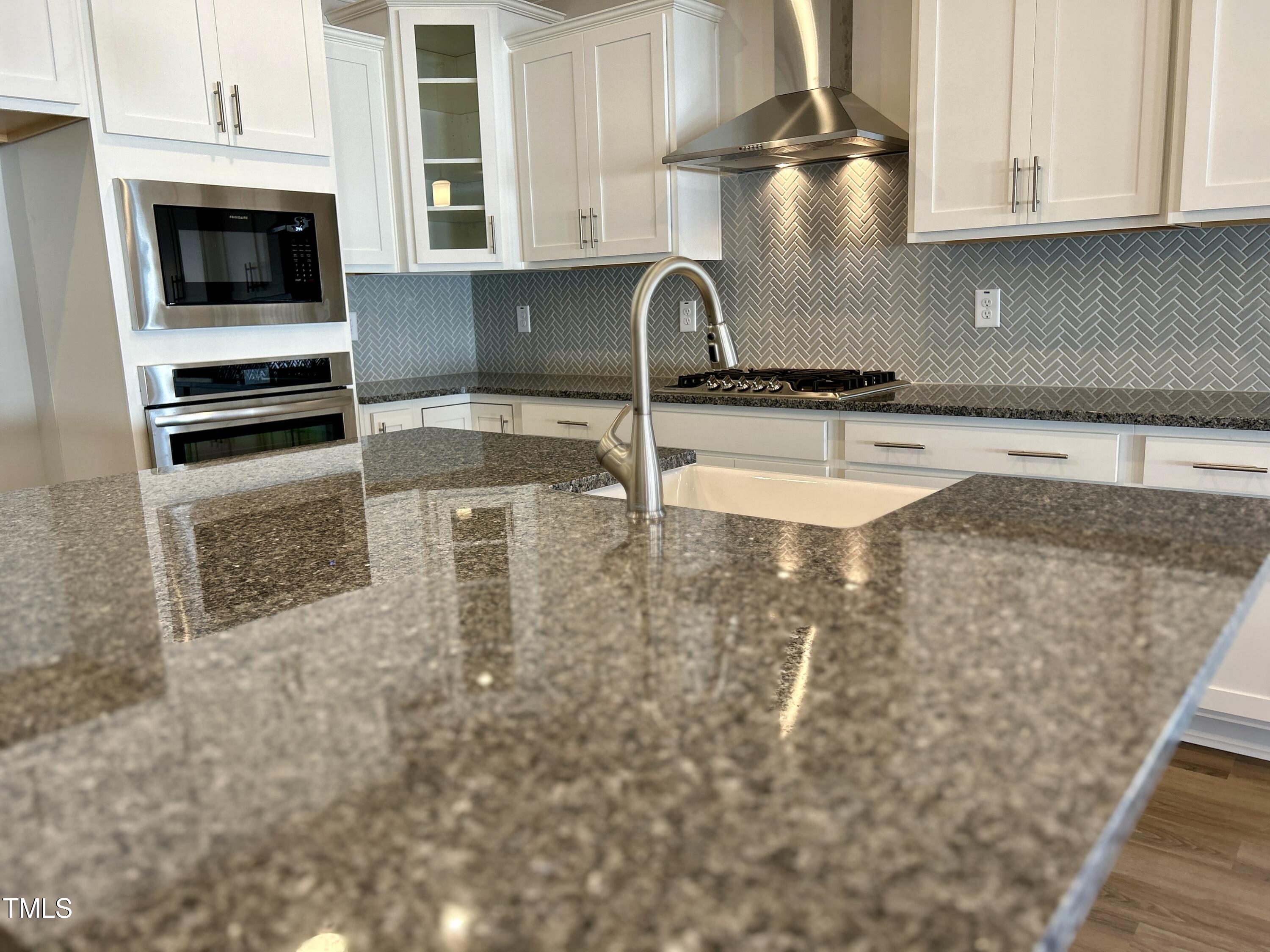 1220 Marsh Hawk Way Wake Forest, NC 27587 - Photo 5 of 23 a kitchen with granite countertop a sink a stove and cabinets