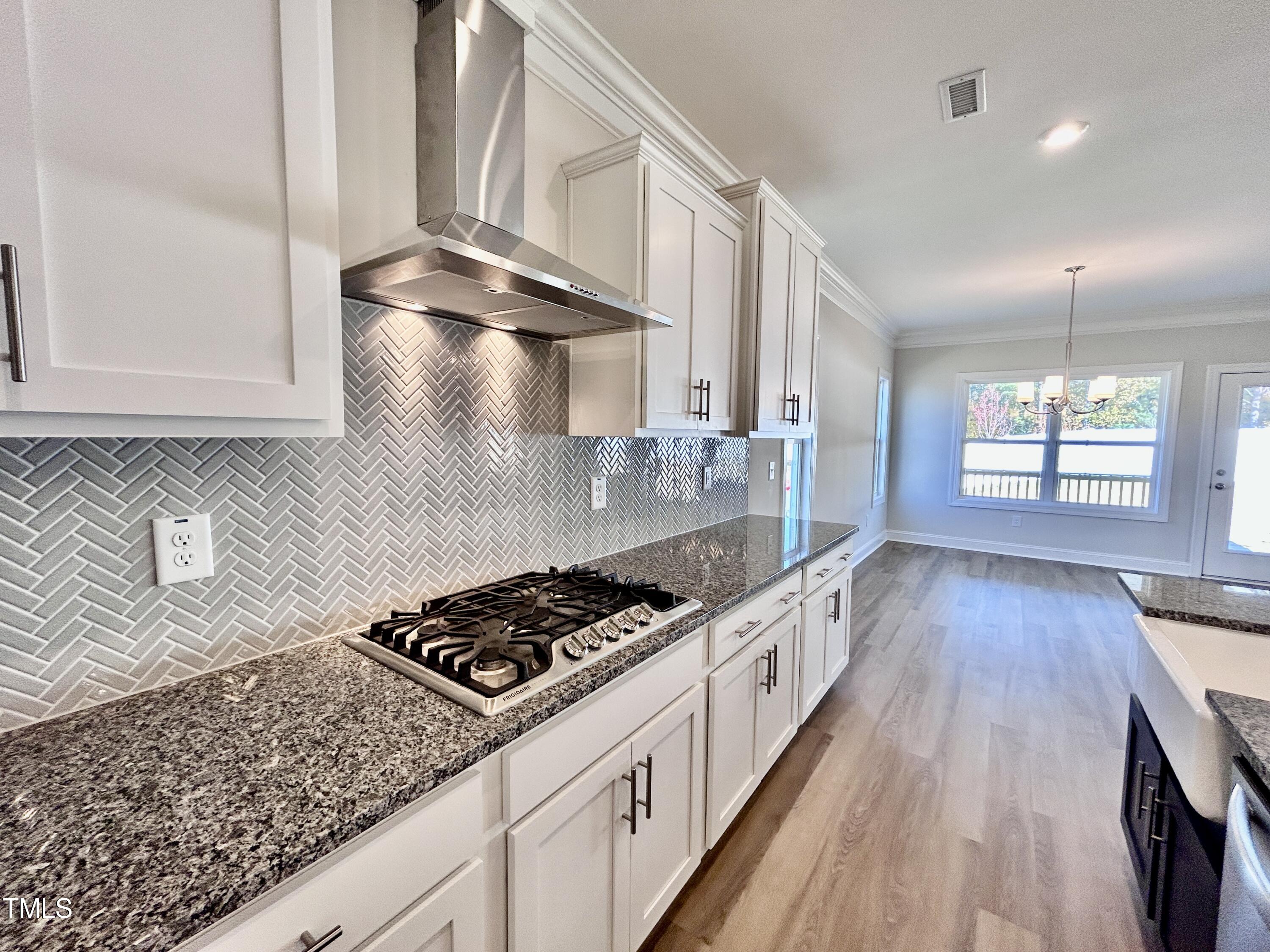 1220 Marsh Hawk Way Wake Forest, NC 27587 - Photo 7 of 23 a kitchen with granite countertop a stove a sink dishwasher and white cabinets with wooden floor