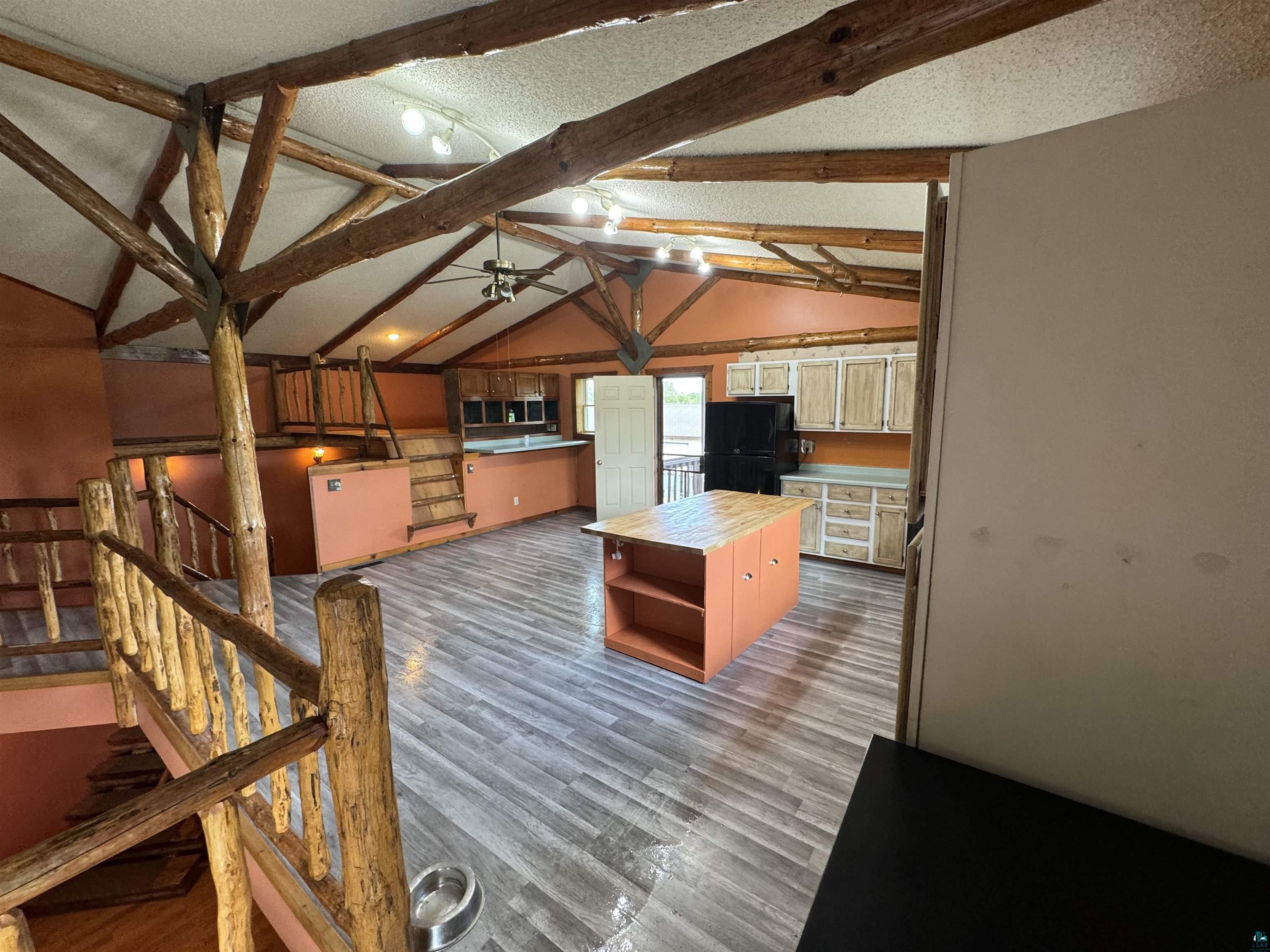 7264 NE Road Wright, MN 55798 - Photo 3 of 17 Kitchen featuring ceiling fan, lofted ceiling with beams, black refrigerator, and hardwood / wood-style flooring