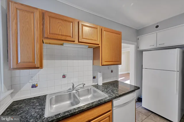 a kitchen with granite countertop stainless steel appliances a sink refrigerator and cabinets