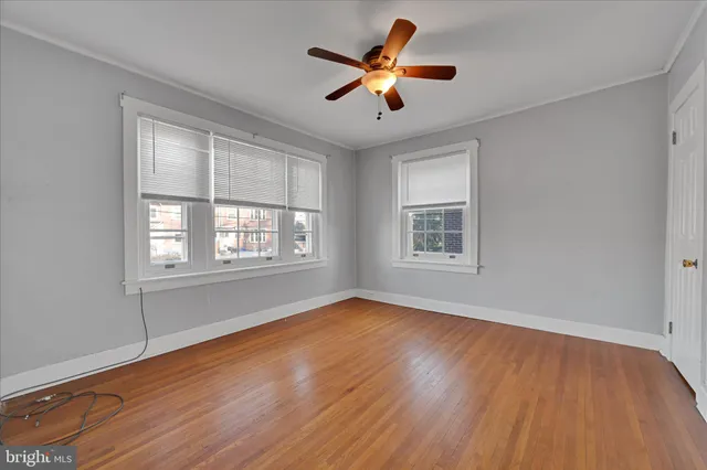 a view of empty room with wooden floor and fan