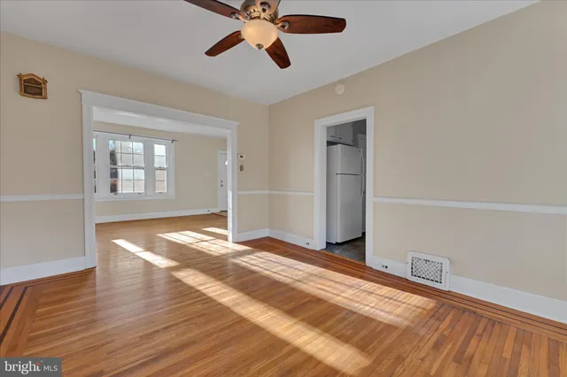 a view of empty room with wooden floor and fan