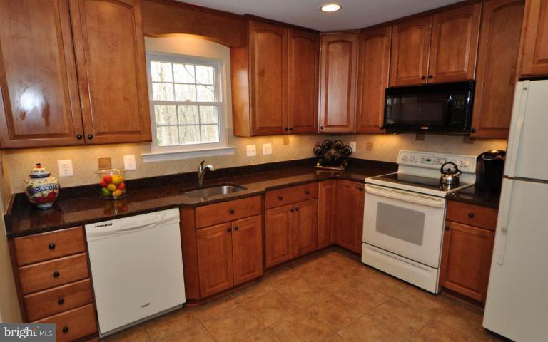 812 Potomac Ridge Court Sterling, VA 20164 - Photo 9 of 30 a kitchen with granite countertop wooden cabinets stainless steel appliances a sink and a window