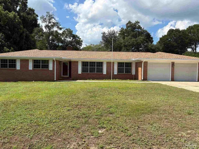 a front view of a house with a garden and trees