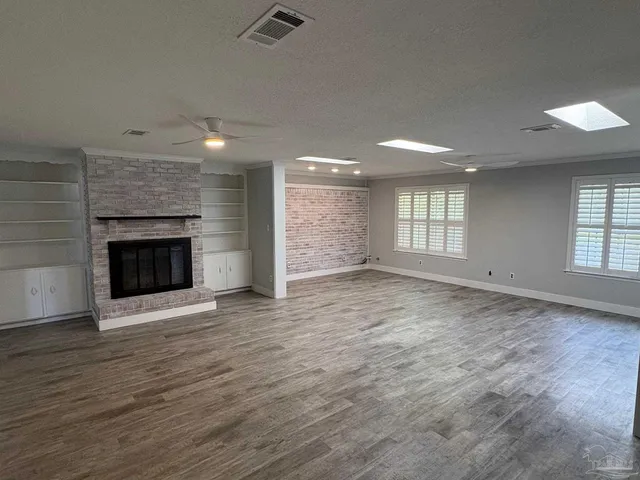 an empty room with windows and fireplace