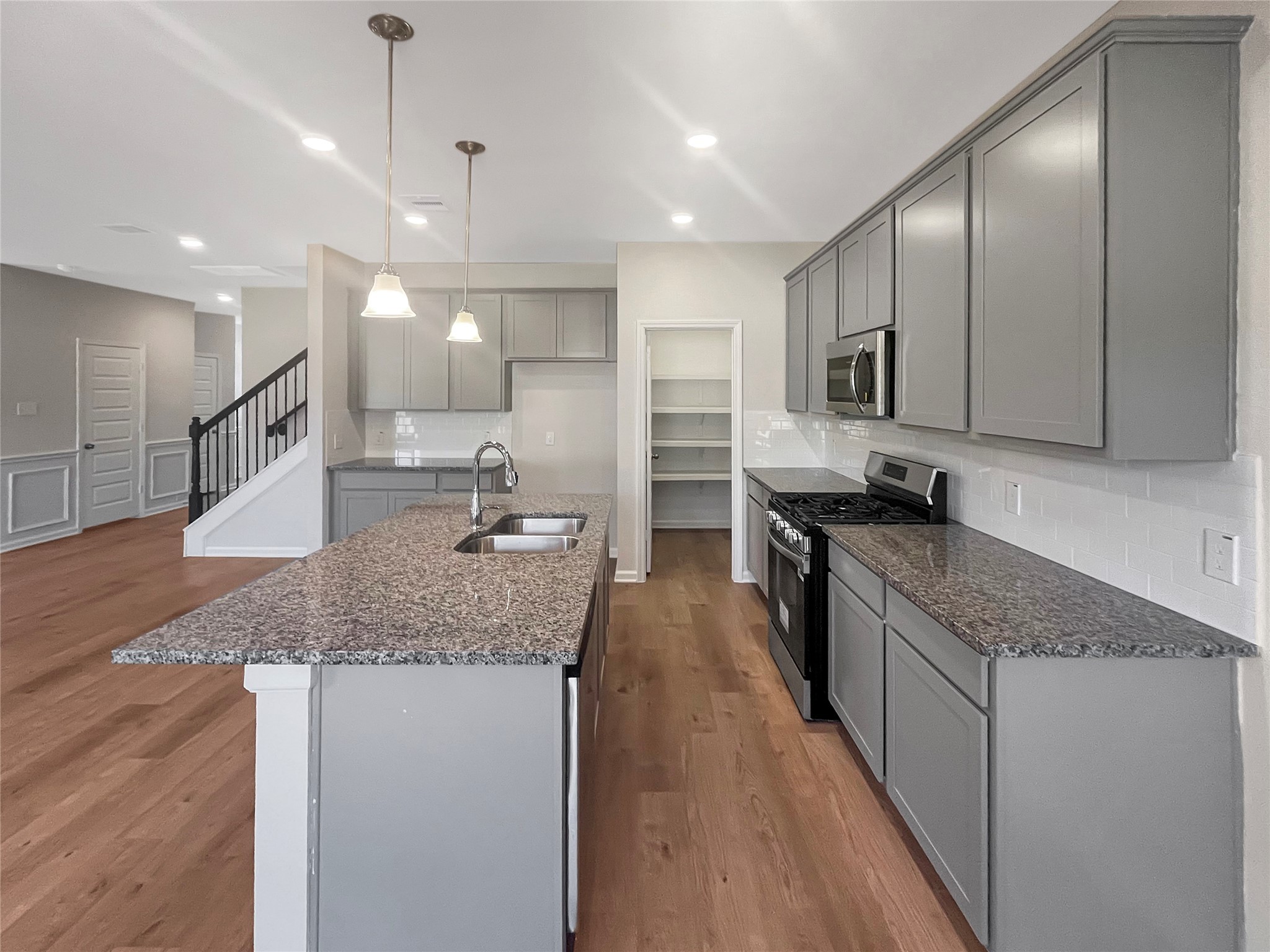 9758 Enclave Ridge Road Willis, TX 77318 - Photo 11 of 25 a large kitchen with a center island wooden floor stainless steel appliances and a counter top space
