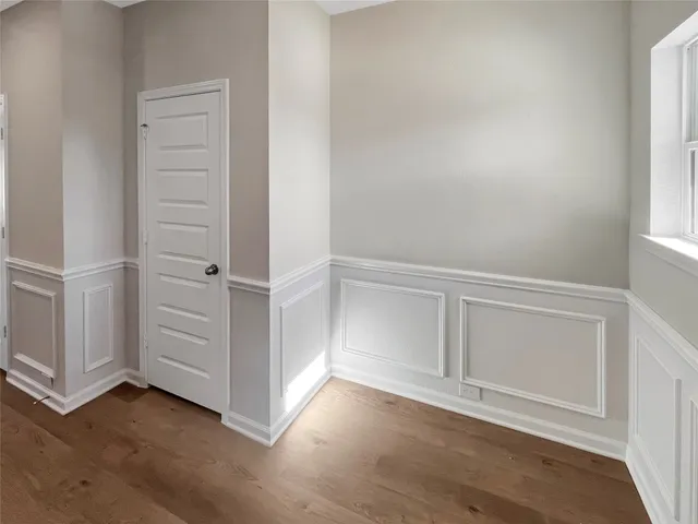 an empty room with wooden floor cabinet and windows
