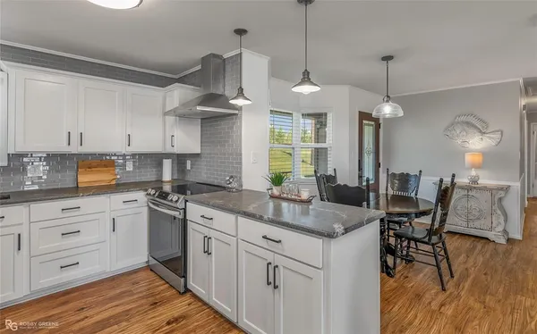 a kitchen with stainless steel appliances granite countertop a sink a stove and a wooden floors
