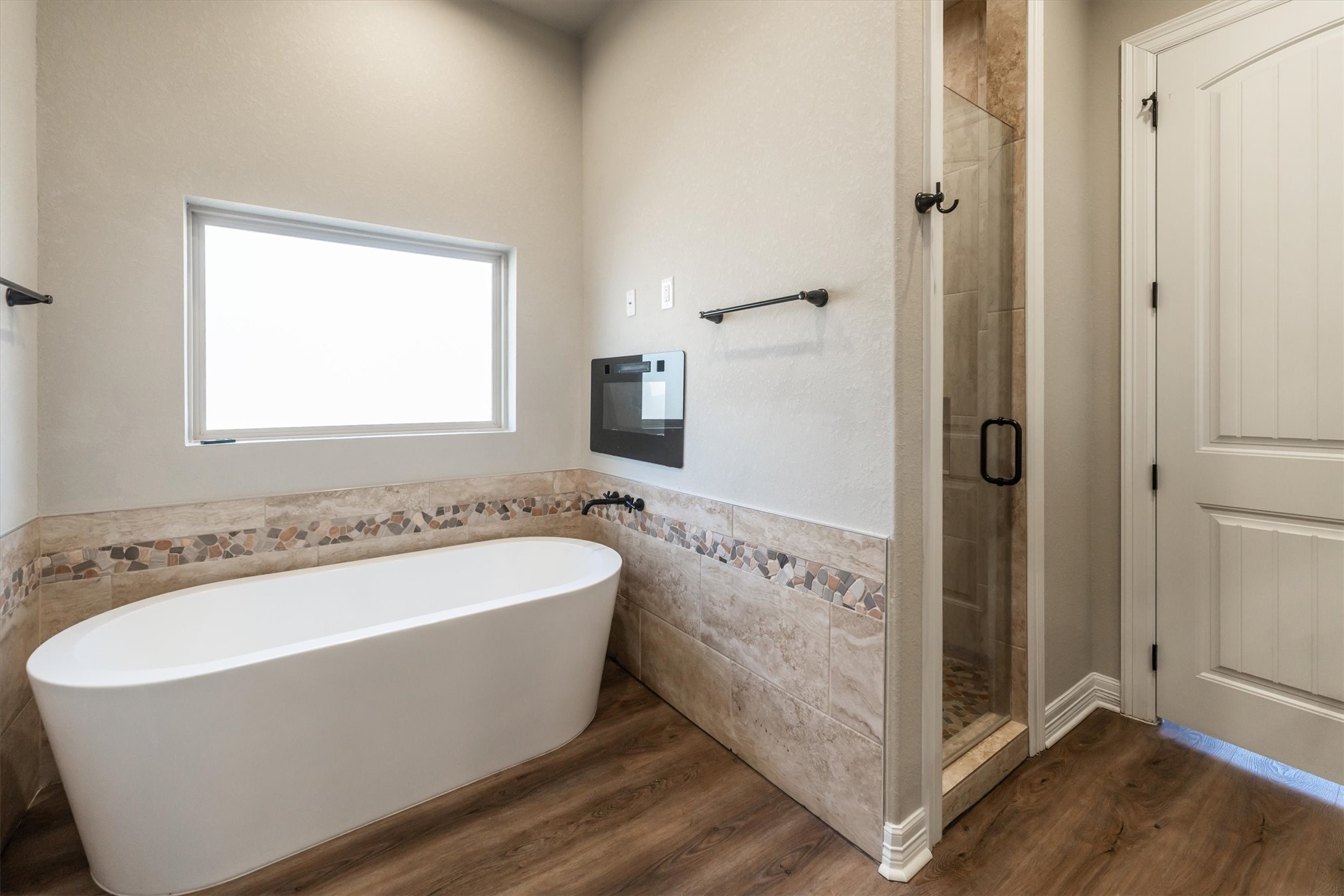 2172 Greentree Drive Huntsville, TX 77340 - Photo 30 of 45 Spa-inspired primary bathroom featuring oversized tub, natural light, side-entry shower, and cozy electric fireplace.