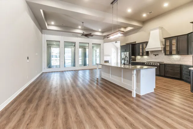 a large kitchen with stainless steel appliances granite countertop a large stove a sink dishwasher and a microwave oven with wooden floor