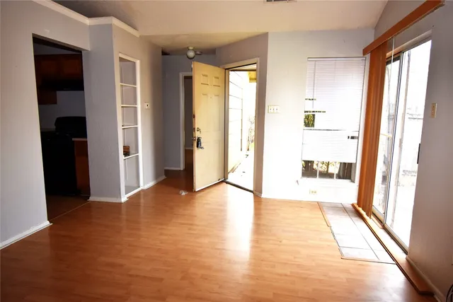 a view of an empty room with wooden floor and a window
