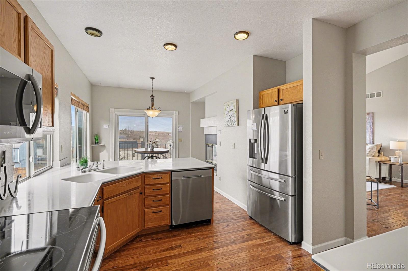 12271 West Chenango Drive Morrison, CO 80465 - Photo 7 of 37 a kitchen with stainless steel appliances a refrigerator a sink dishwasher a stove and white cabinets with wooden floor