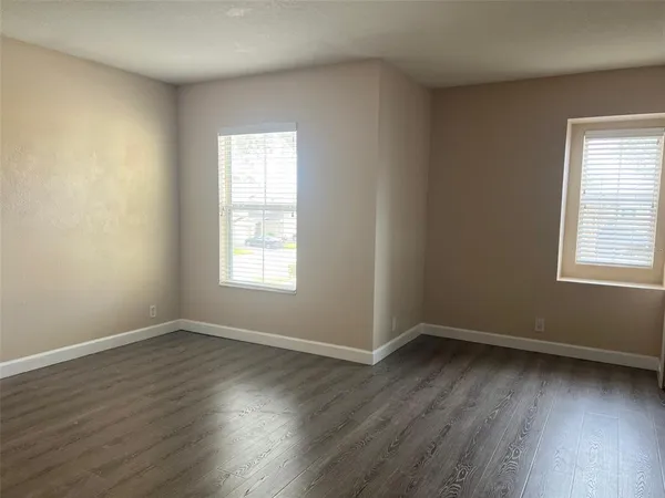 a view of an empty room with wooden floor and closet