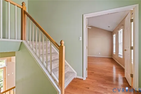 a view of a hallway with wooden floor and stairs