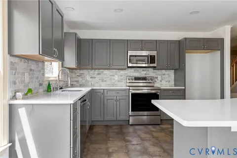 a kitchen with stainless steel appliances a stove a sink a microwave a refrigerator a microwave and cabinets