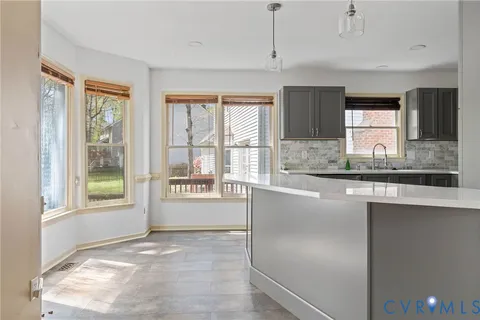 a open kitchen with granite countertop a refrigerator a sink a stove and white cabinets with wooden floor