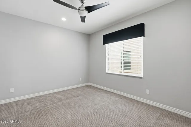 an empty room with a window and a ceiling fan