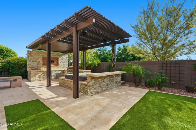 a view of a patio with table and chairs under an umbrella with a barbeque