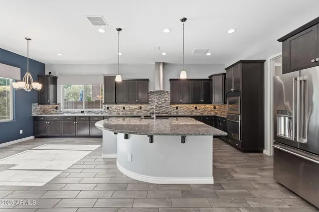 a kitchen with kitchen island a counter top space a sink cabinets and stainless steel appliances