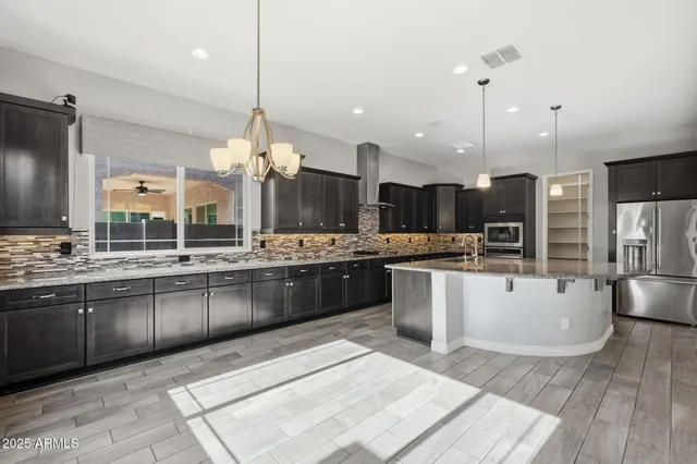 a large kitchen with stainless steel appliances kitchen island granite countertop a sink counter space and a wooden floor