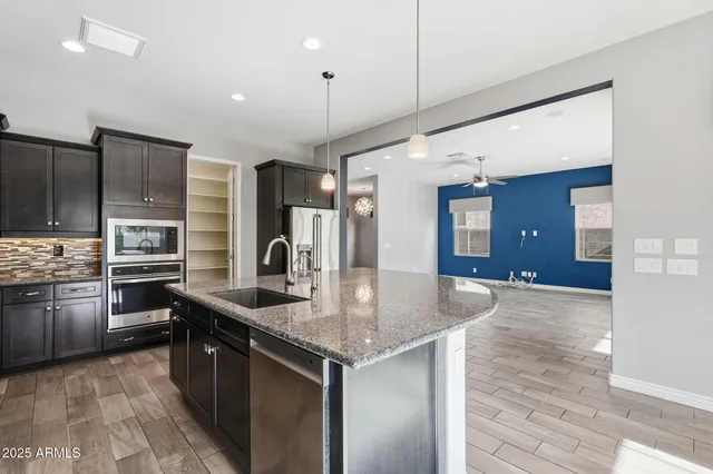 a kitchen with stainless steel appliances granite countertop a sink a stove and a refrigerator