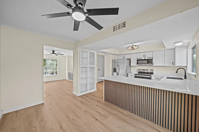 a kitchen with stainless steel appliances white cabinets a sink a stove a window and cabinets