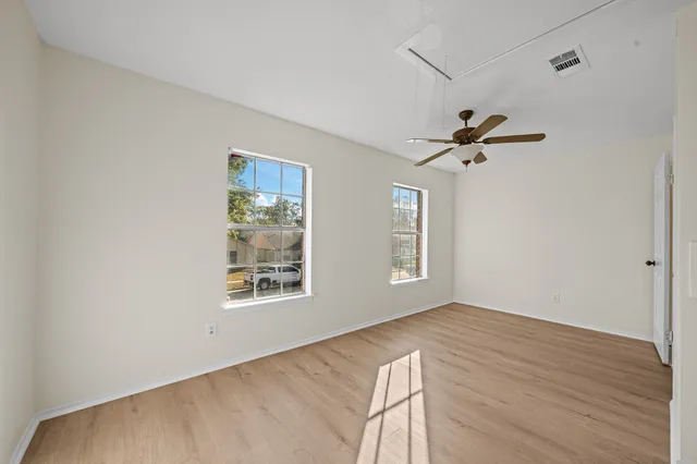 an empty room with wooden floor and windows