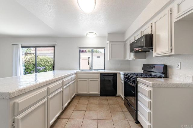 a kitchen with stainless steel appliances granite countertop a stove top oven a sink dishwasher and a microwave oven with white cabinets