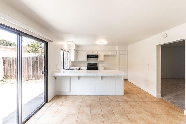 a large white kitchen with a sink and dishwasher a refrigerator with wooden floor