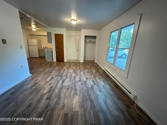 a view of empty room with wooden floor and window