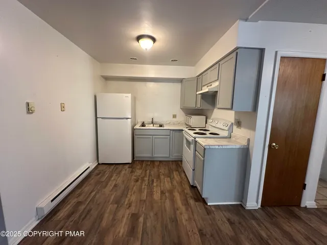 a kitchen with sink a refrigerator and wooden floor